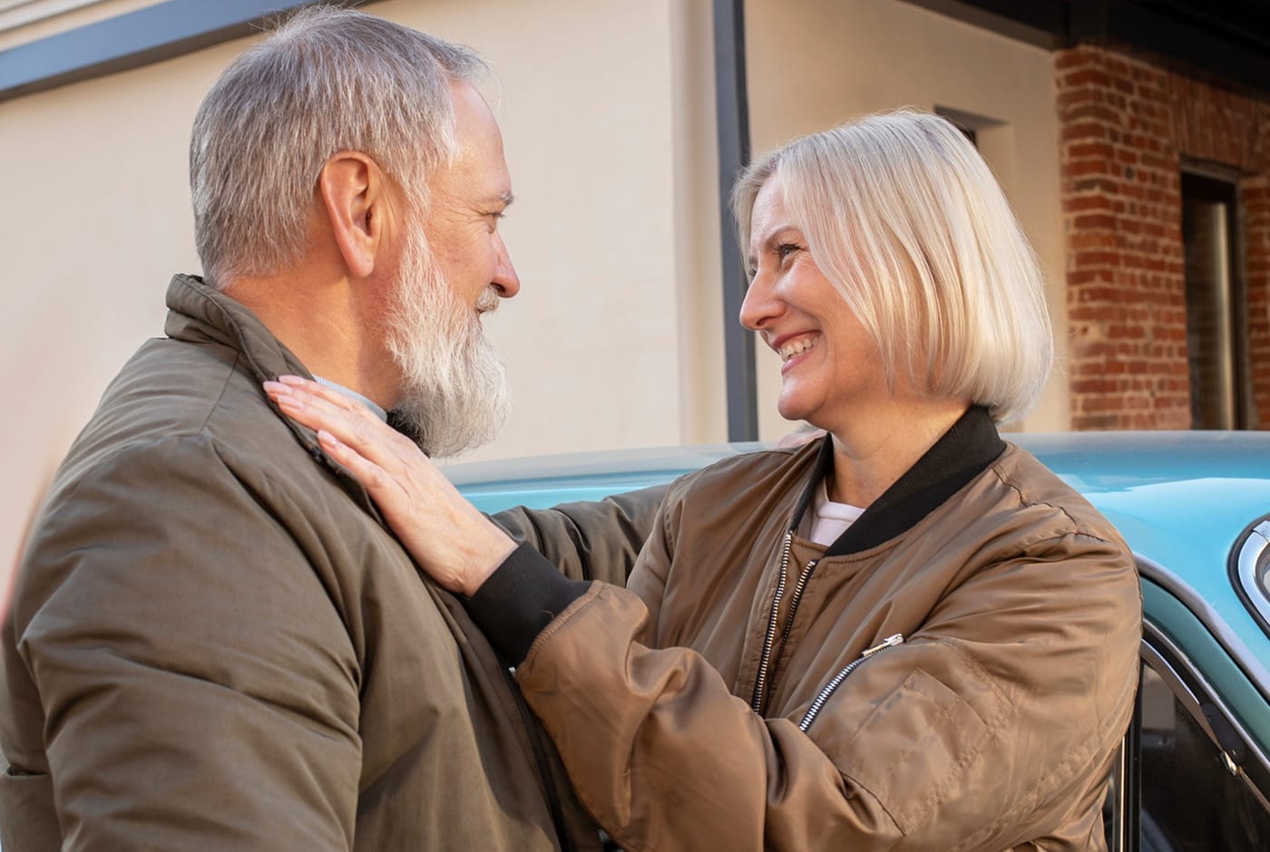 Mature couple smiling warmly at each other near a vintage car outdoors — Sequel Dating App blog
