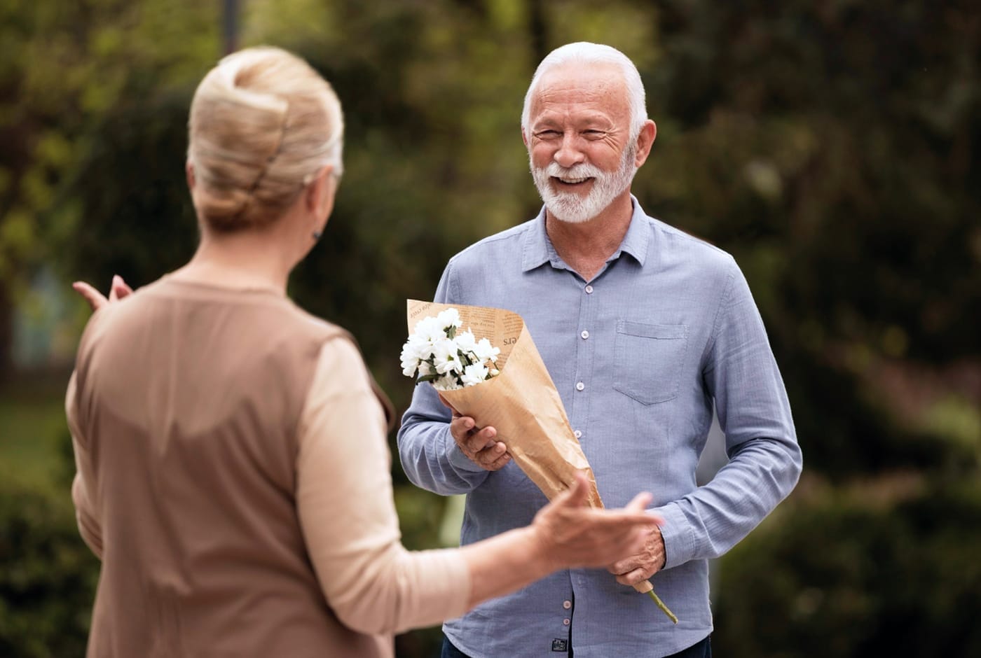 Mature man presenting flowers to a woman on a first date outdoors — Sequel Dating App blog
