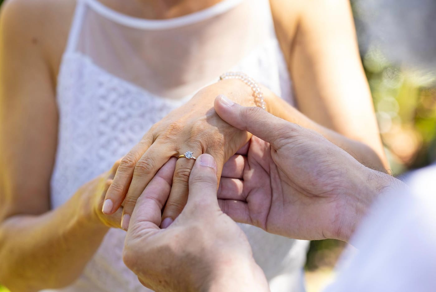 Mature couple exchanging wedding rings during an outdoor ceremony